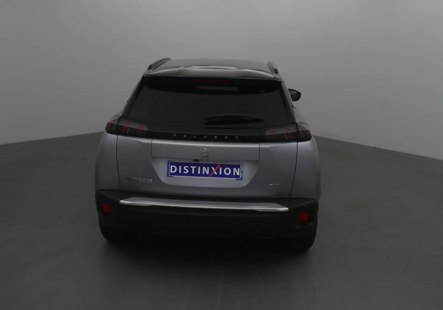 Vue arrière d'un Peugeot 2008 électrique gris Artense avec toit noir et feux arrière caractéristiques en forme de griffes.