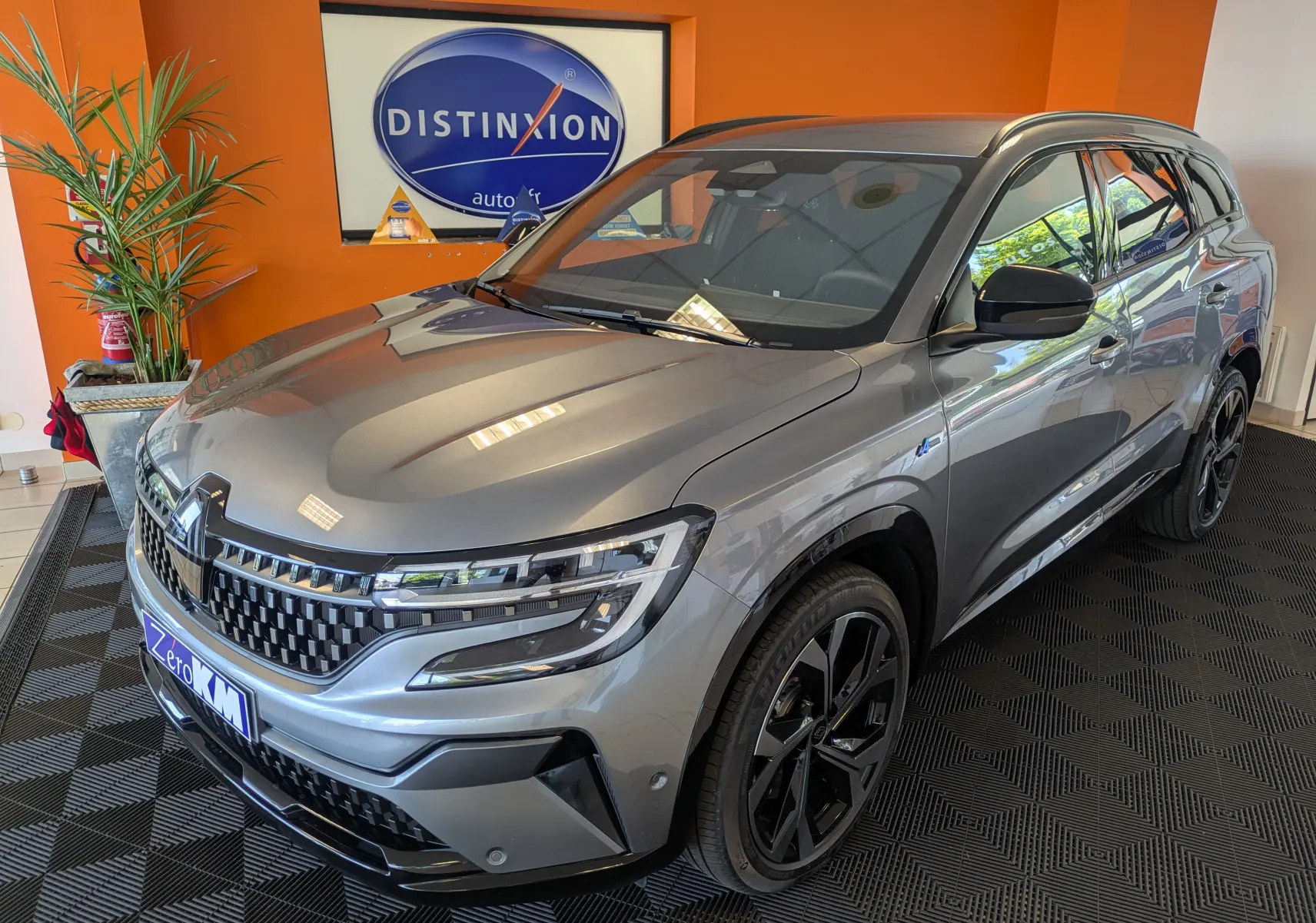 Renault Espace VI gris schiste en 3/4 avant droit, avec jantes alliage 20'' Daytona et barres de toit noires.