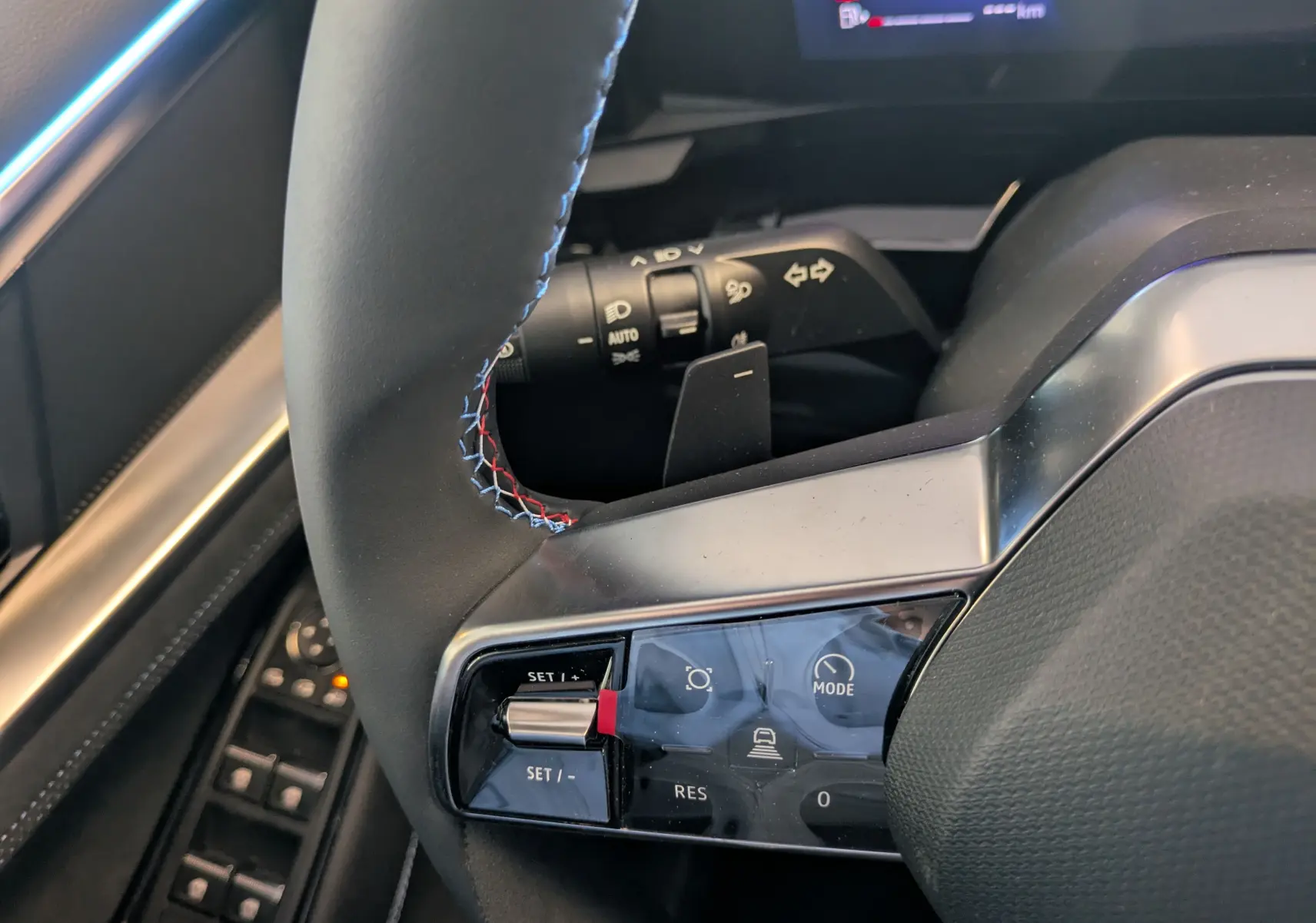 Gros plan sur le volant du Renault Espace VI gris schiste, avec commandes intégrées et surpiqûres tricolores.