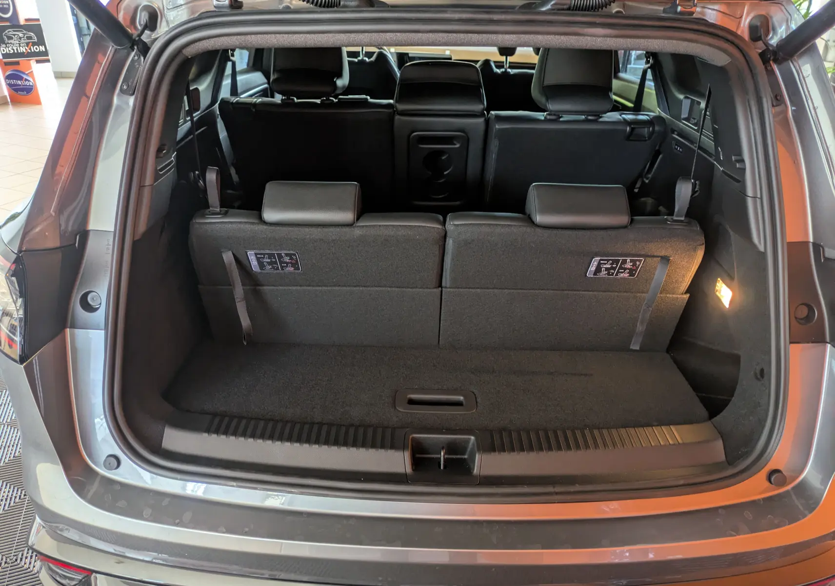 Coffre ouvert vu de l'arrière d'un Renault Espace VI gris schiste, montrant la troisième rangée de sièges relevée.