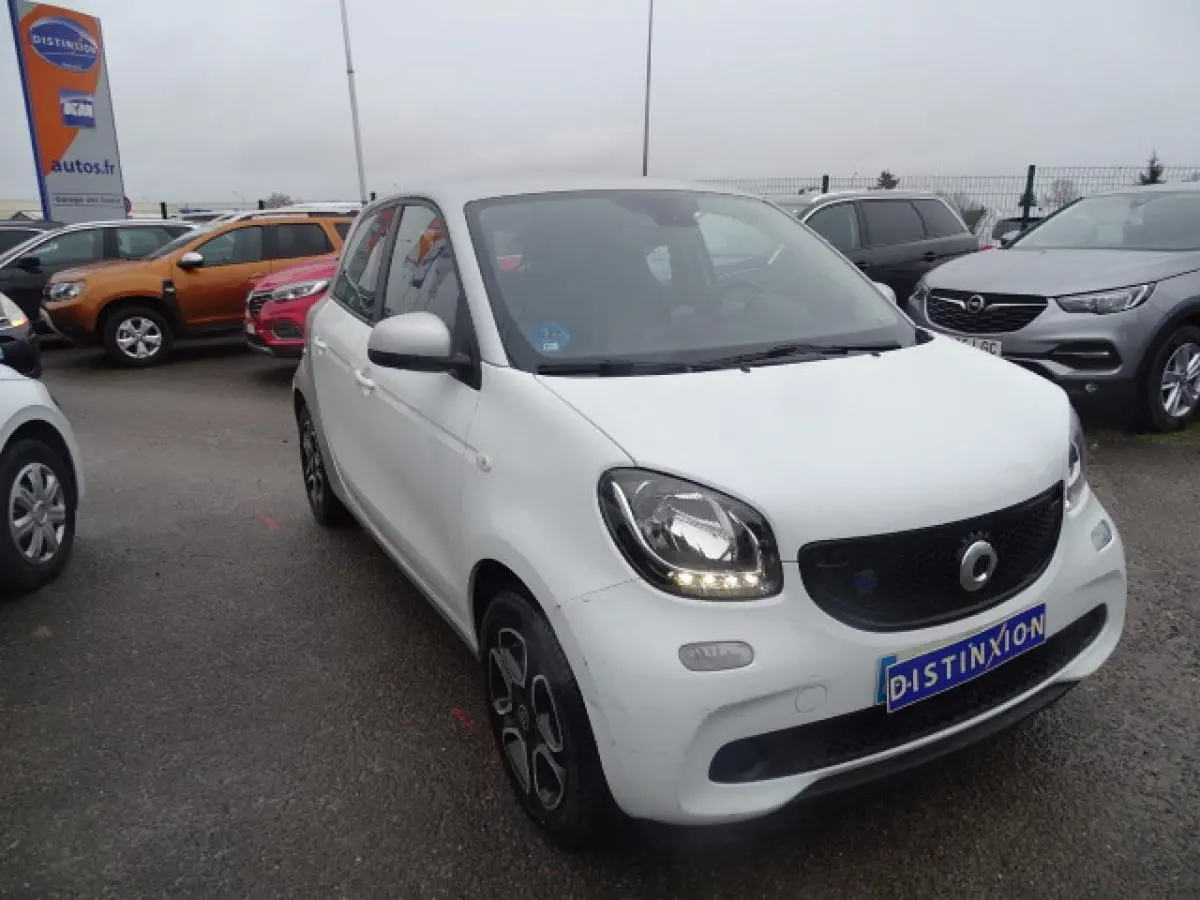 Vue 3/4 avant gauche d'une Smart Forfour électrique blanche avec calandre noire brillante et jantes alliage bicolores.