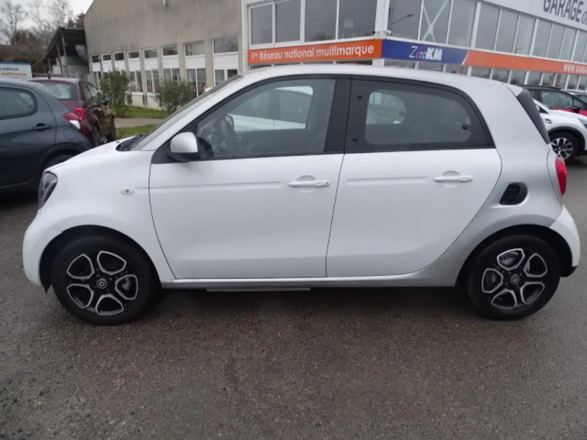Vue latérale droite d'une Smart Forfour Electric Drive Prime blanche avec jantes alliage bicolores et calandre noir brillant.