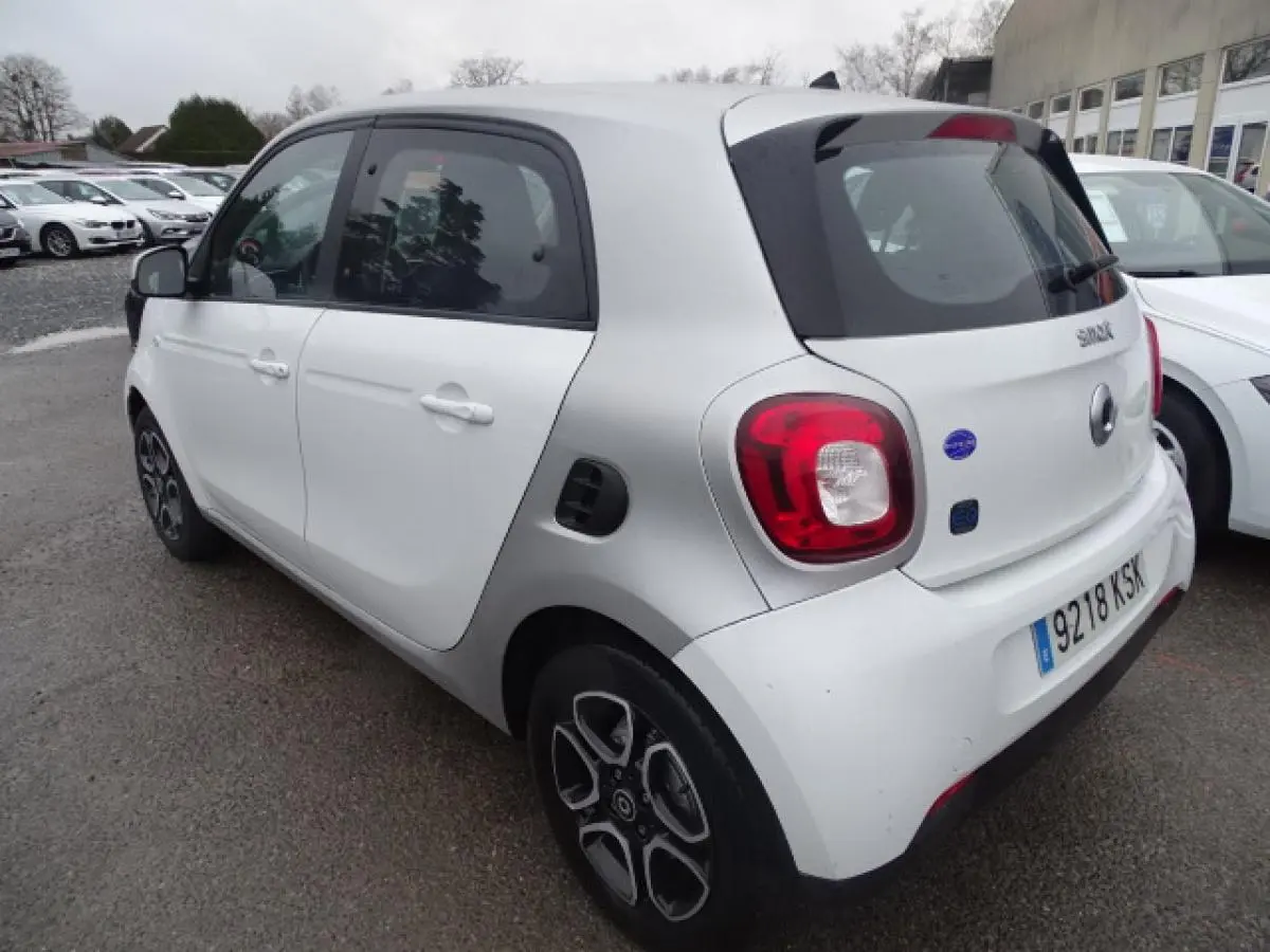 Vue 3/4 arrière droite d'une Smart Forfour Electric Drive blanche avec jantes alliage bicolores et logo EQ visible.