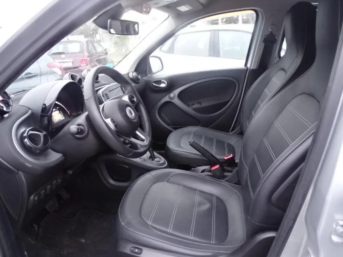 Intérieur côté conducteur d'une Smart Forfour blanc, sièges cuir noir et volant multifonctions en vue rapprochée.