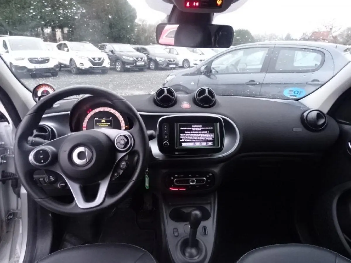 Vue intérieure avant du Smart Forfour Electric Drive Prime blanc, volant cuir multifonctions et écran tactile central visible.