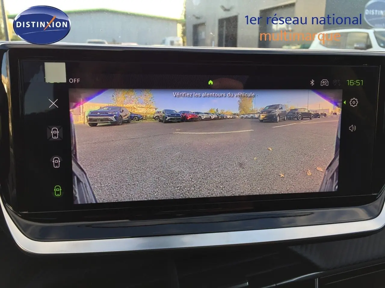 Vue de la caméra de recul affichée sur l'écran intérieur d'une Peugeot 208 gris Artense, montrant le parking derrière.