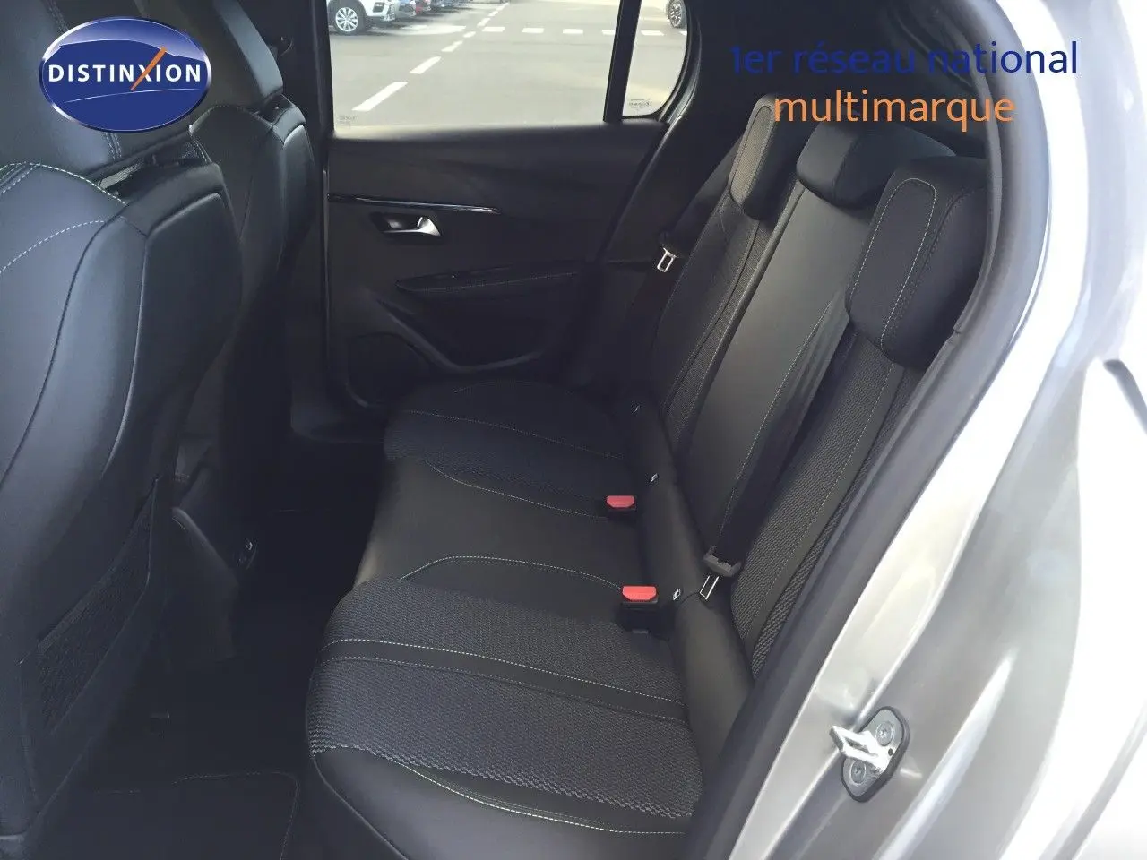 Vue intérieure côté arrière droit montrant les sièges arrière noirs avec surpiqûres vertes d'une Peugeot 208 gris Artense 2025.
