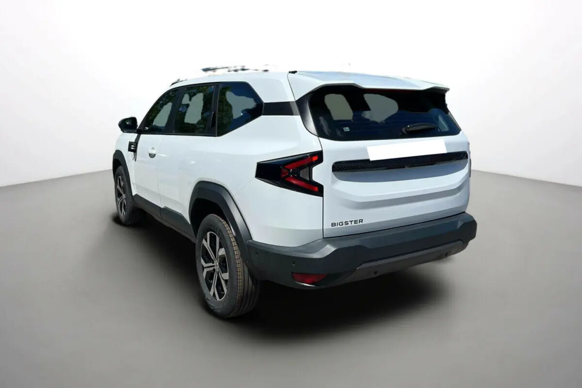 Vue 3/4 arrière droite du SUV Dacia Bigster blanc glacier avec jantes alu et barres de toit noires.