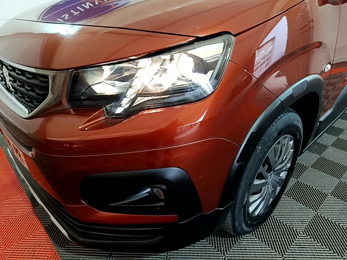 Gros plan sur l'avant droit marron du Peugeot Rifter 2019, mettant en valeur le phare LED et la calandre noire.