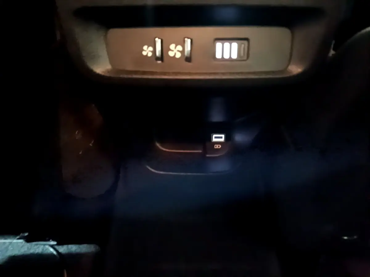 Vue rapprochée des commandes de ventilation arrière et prise USB dans l'habitacle sombre d'un Peugeot Rifter marron 2019 BlueHDi Allure.