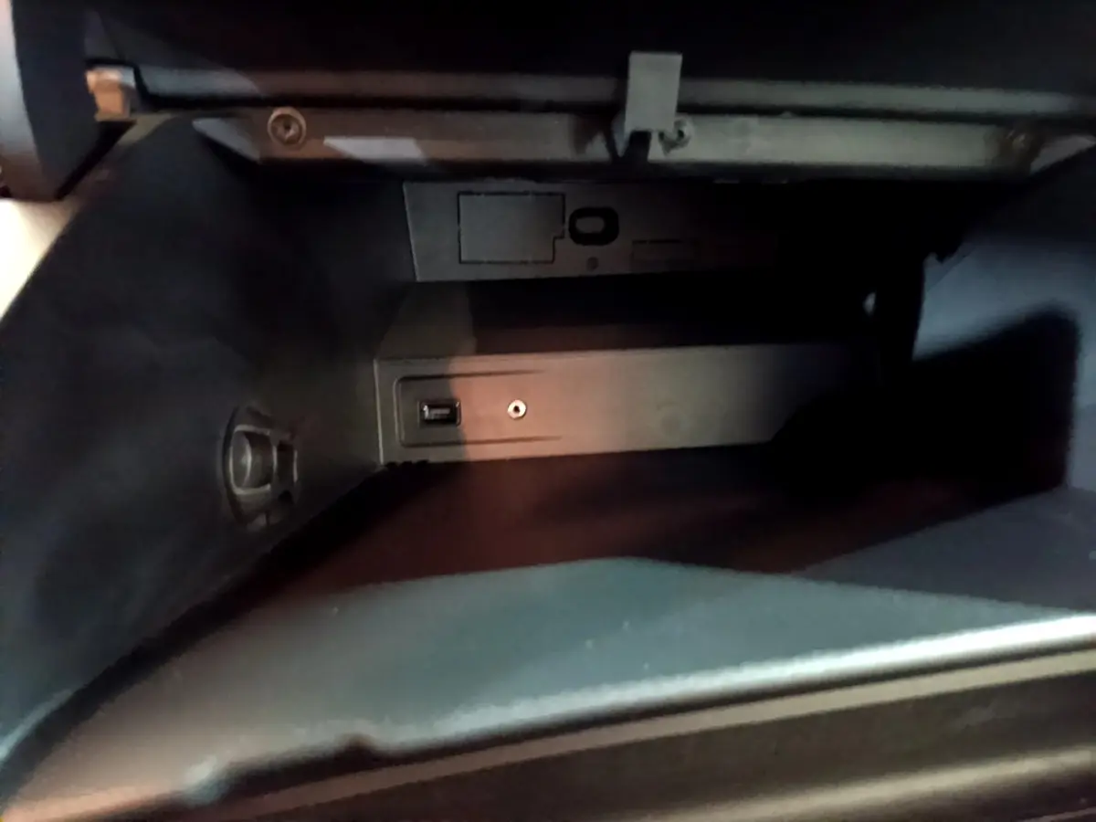 Vue rapprochée de la boîte à gants noire du Peugeot Rifter BlueHDi 100 Allure 2019 avec prise USB et prise auxiliaire.