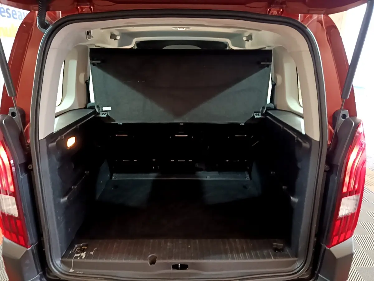 Coffre ouvert vu de l'arrière d'un Peugeot Rifter marron 2019, montrant l'espace de chargement vide et les feux arrière allumés.