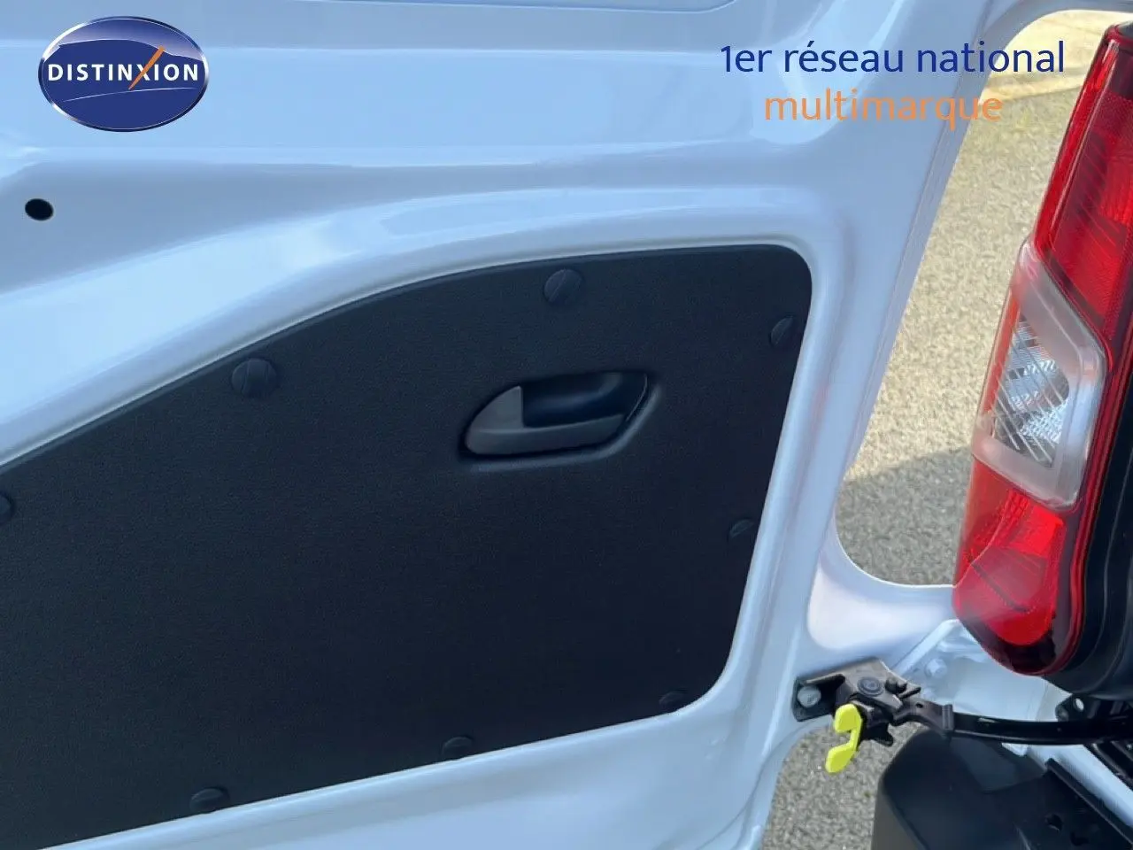 Gros plan sur l’intérieur de la porte arrière droite blanche du Citroën Berlingo 2025, avec poignée noire et feu arrière visible.