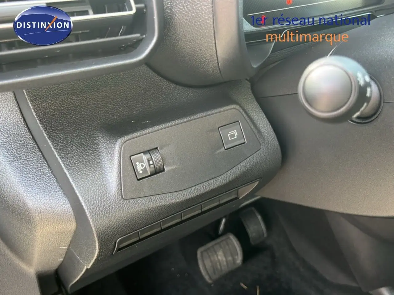 Détail de la console côté gauche avec commandes d’éclairage et rétroviseur, pédales visibles, intérieur noir du Citroën Berlingo 2025.