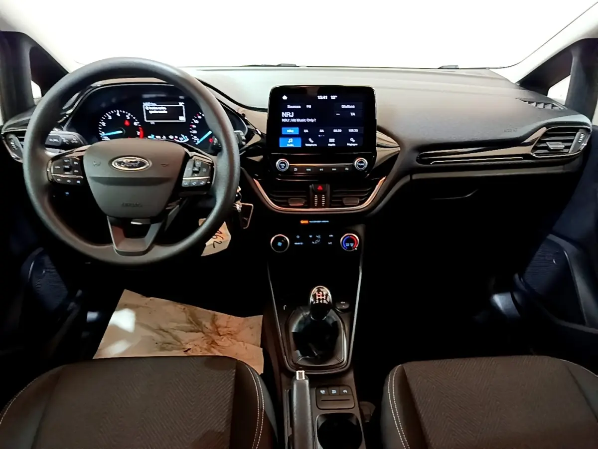 Vue intérieure avant de la Ford Fiesta 1.1 75ch COOL & CONNECT 2022, tableau de bord noir avec écran tactile et boîte manuelle.