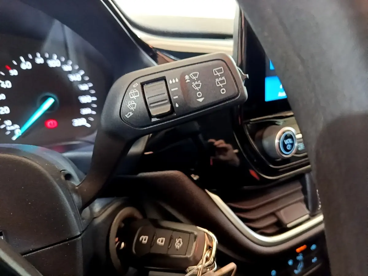 Gros plan intérieur sur la commande d’essuie-glace et le tableau de bord numérique d’une Ford Fiesta 2022 blanche.