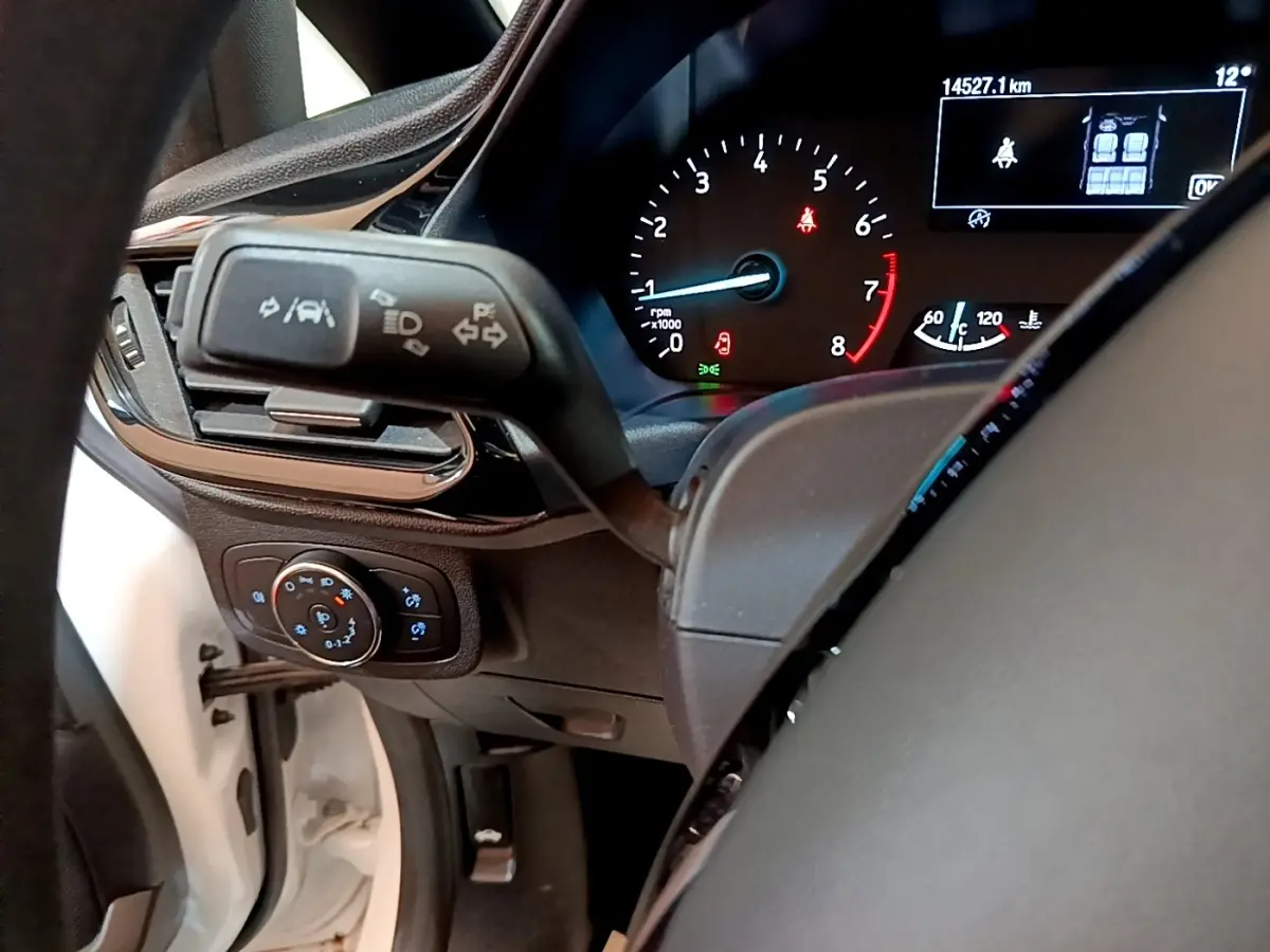 Vue intérieure du tableau de bord de la Ford Fiesta blanche, avec affichage numérique et commandes au volant visibles.