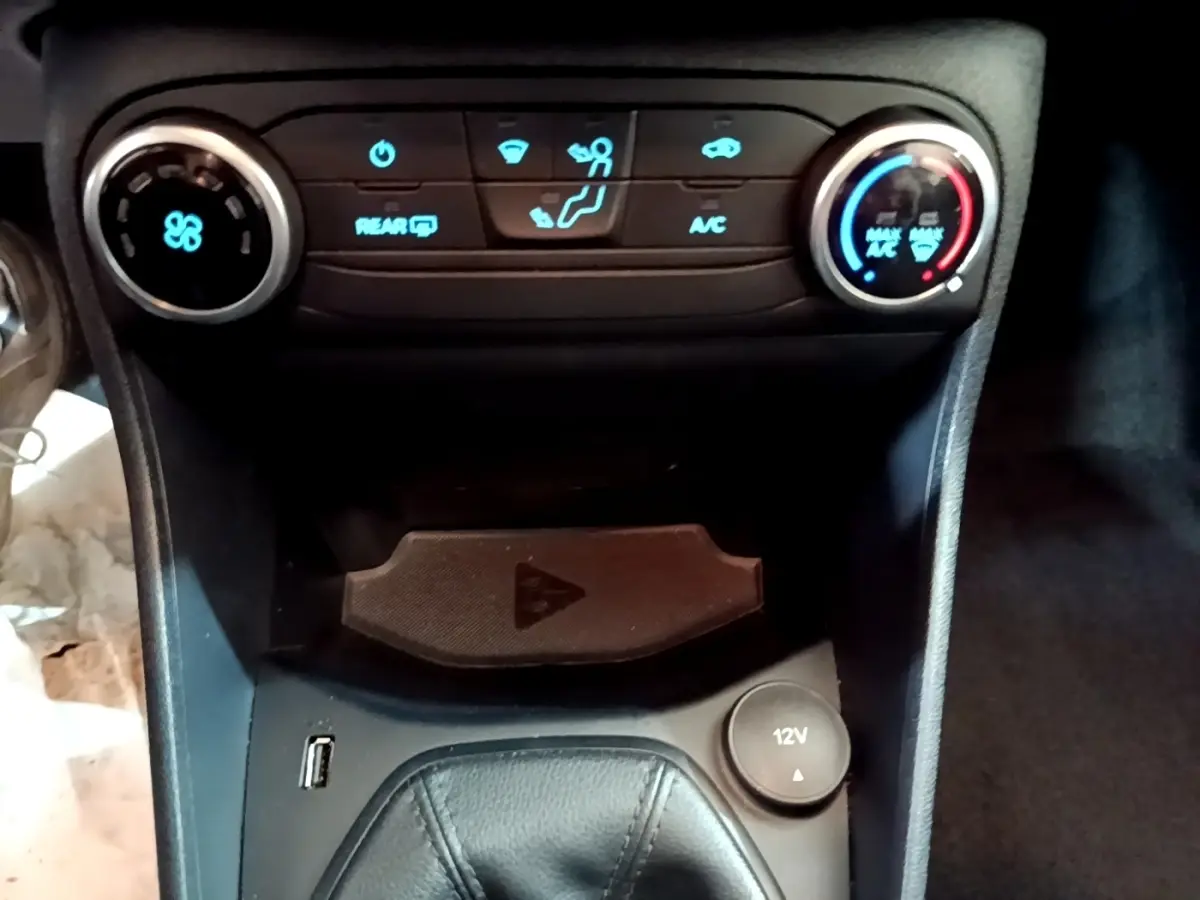 Vue rapprochée de la console centrale noire de la Ford Fiesta 2022, avec commandes climatisation et prise 12V visible.