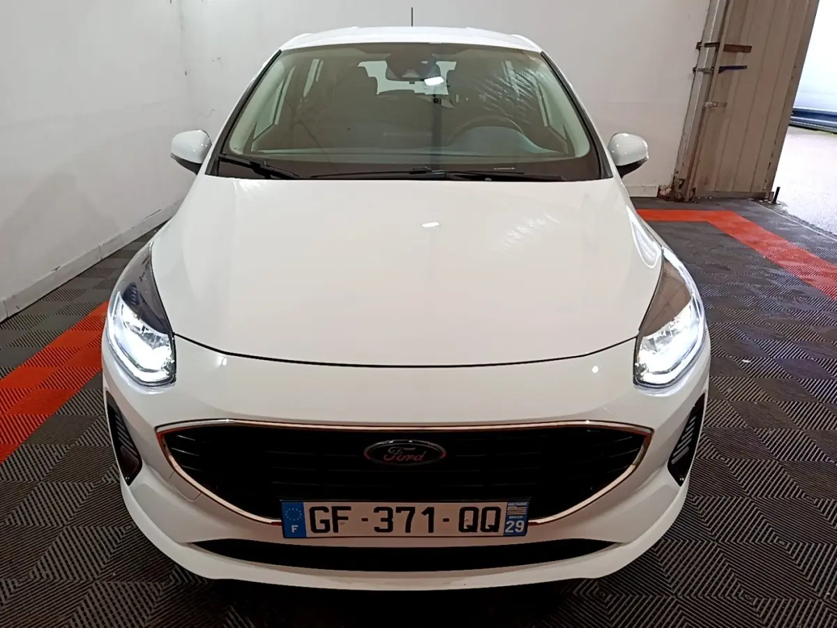 Vue avant d'une Ford Fiesta blanche 2022 avec phares LED allumés dans un garage.