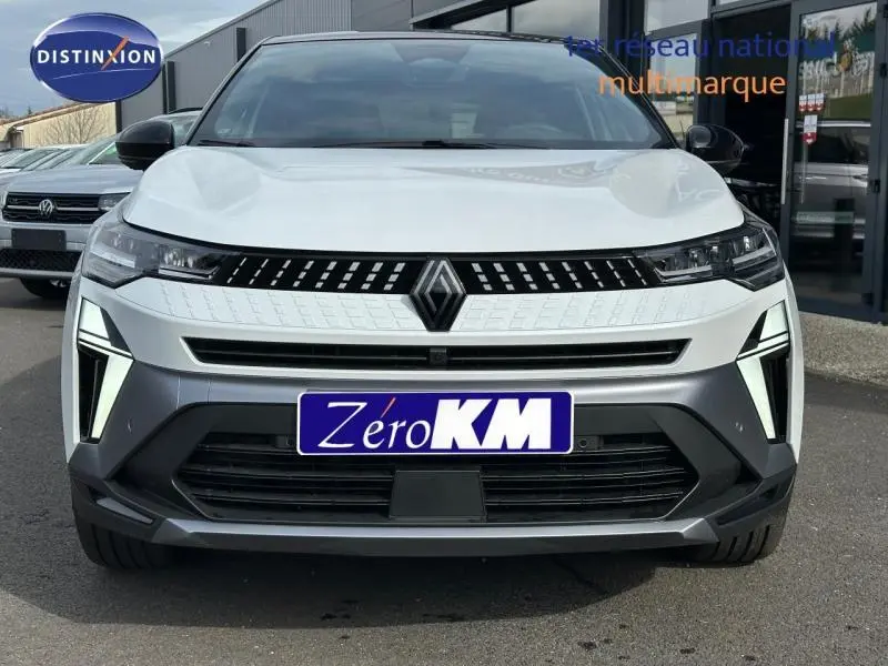 Vue frontale du Renault Captur 1.8 E-Tech hybride 2026 en blanc nacré avec toit noir et signature lumineuse distinctive.