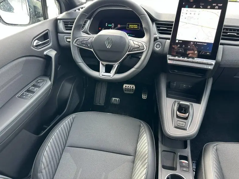Vue intérieure de face du poste de conduite du Renault Captur 1.8 E-Tech 2026 avec volant multifonction et écran tactile vertical.