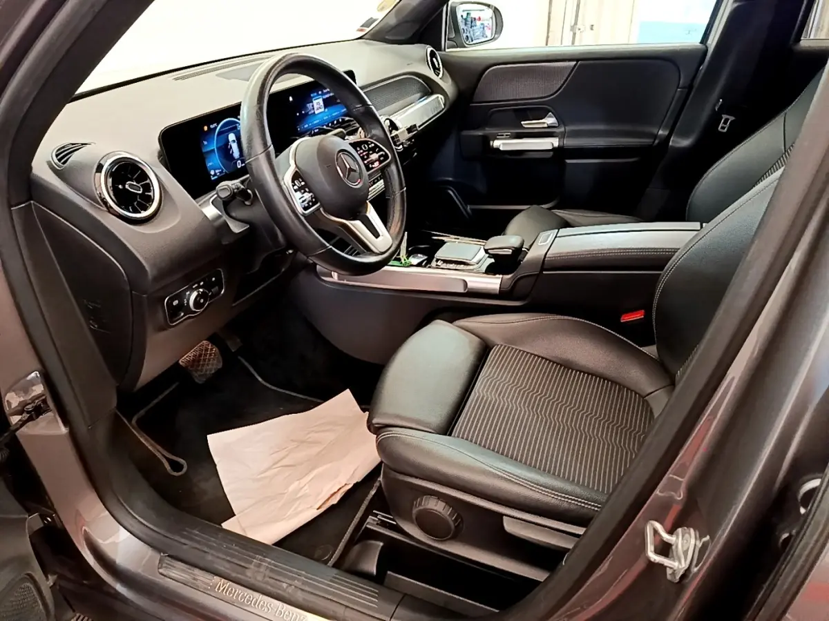 Intérieur avant droit du Mercedes GLB 200 d Business Line 2021 gris foncé, avec tableau de bord numérique et volant cuir.