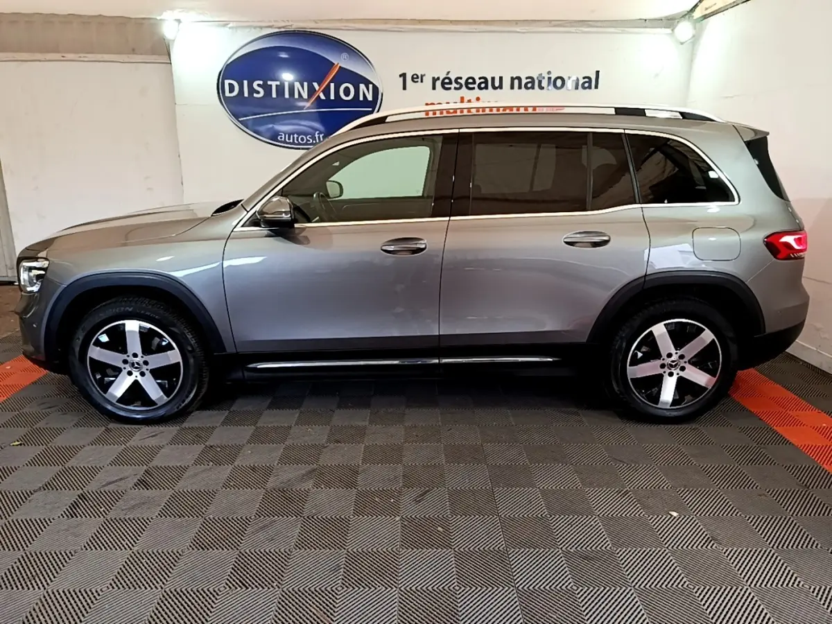 Vue de profil côté gauche d’un Mercedes GLB 200 d Business Line gris foncé en intérieur avec jantes alliage cinq branches.