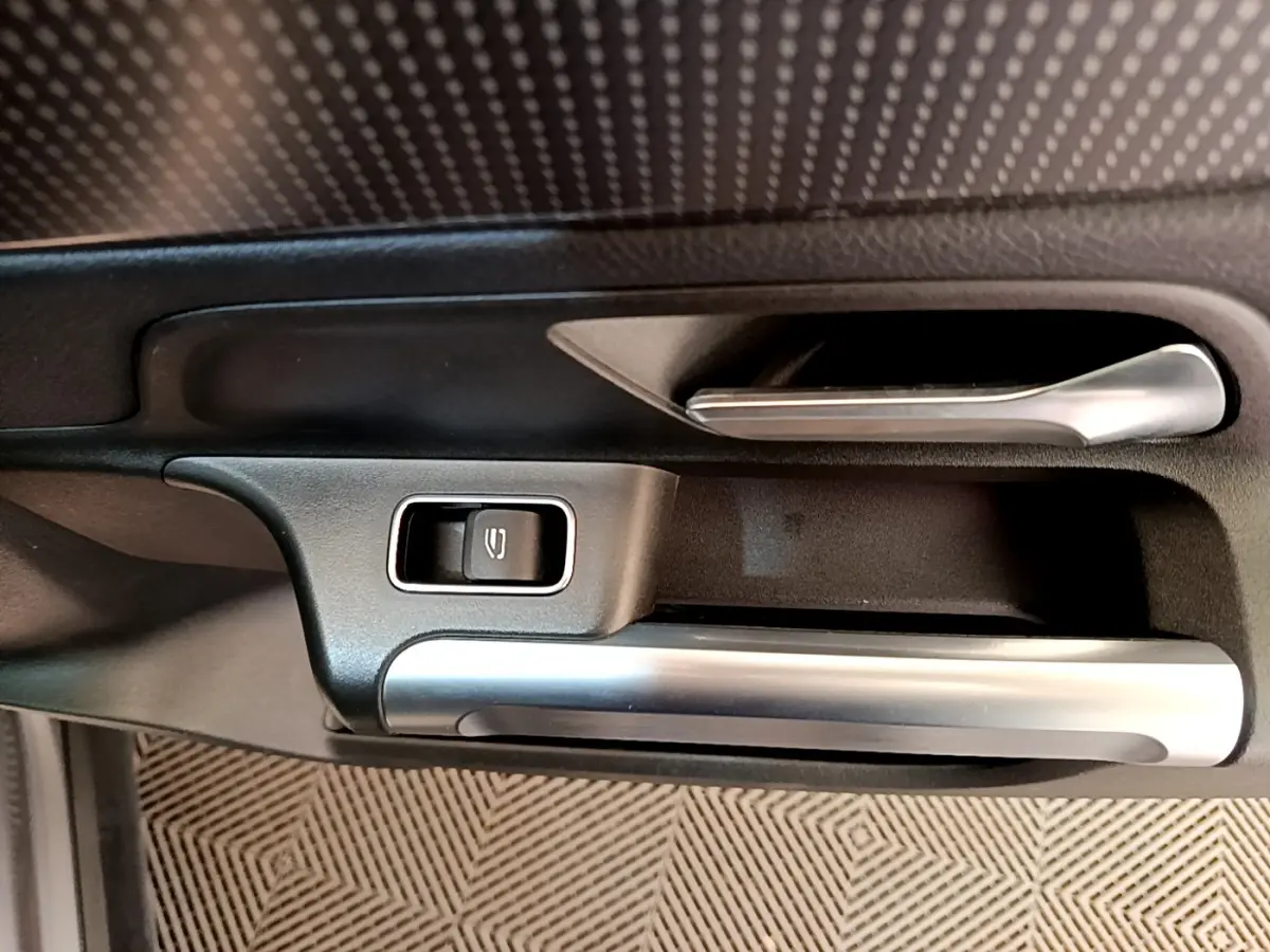 Gros plan sur la poignée intérieure côté gauche avec bouton de verrouillage, finition argent et noir du Mercedes GLB 200 d.