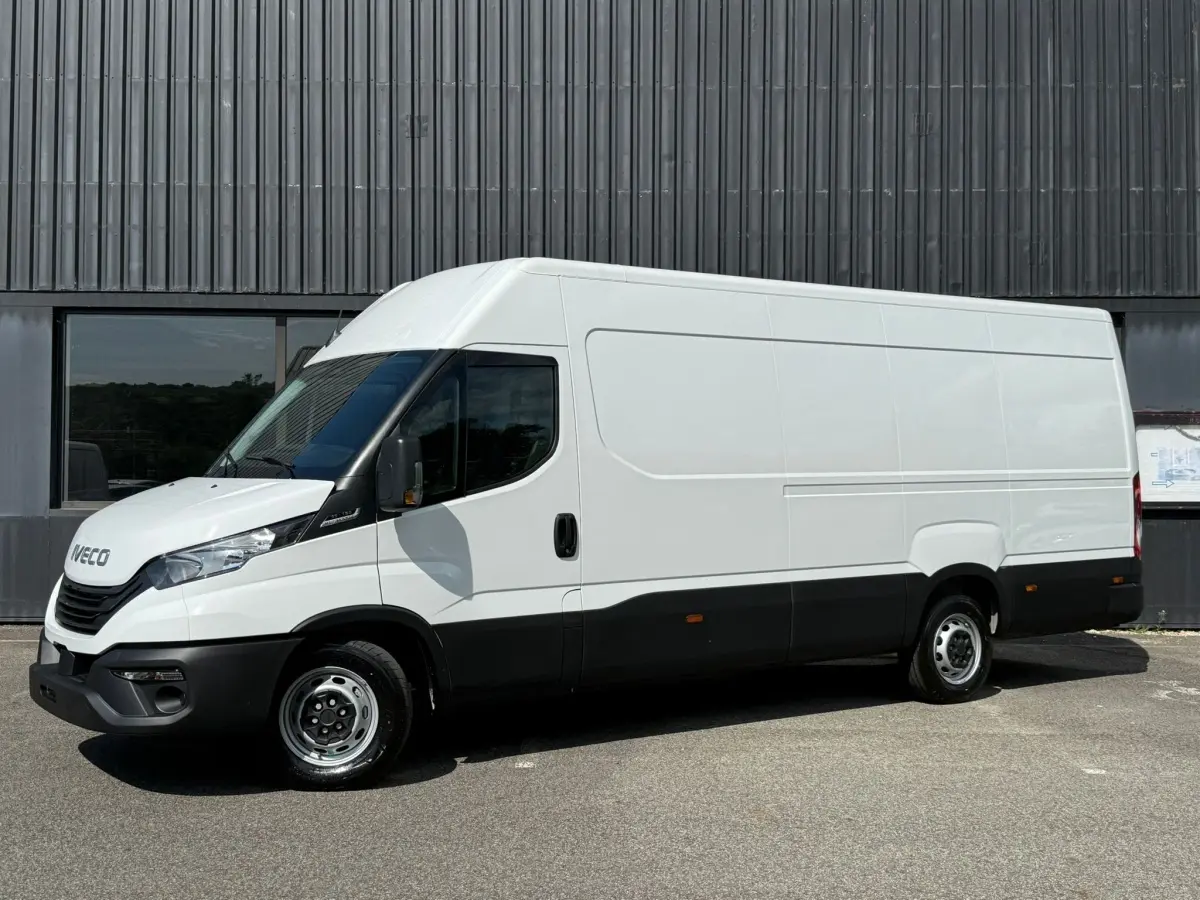 Fourgon Iveco Daily blanc vu de profil côté gauche, avec bas de caisse noir et porte latérale coulissante.