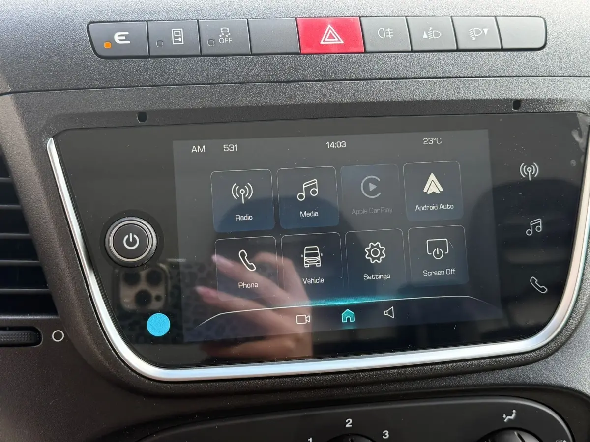 Vue rapprochée de l’écran tactile central du tableau de bord du Iveco Daily blanc, affichant les options multimédia et connectivité.