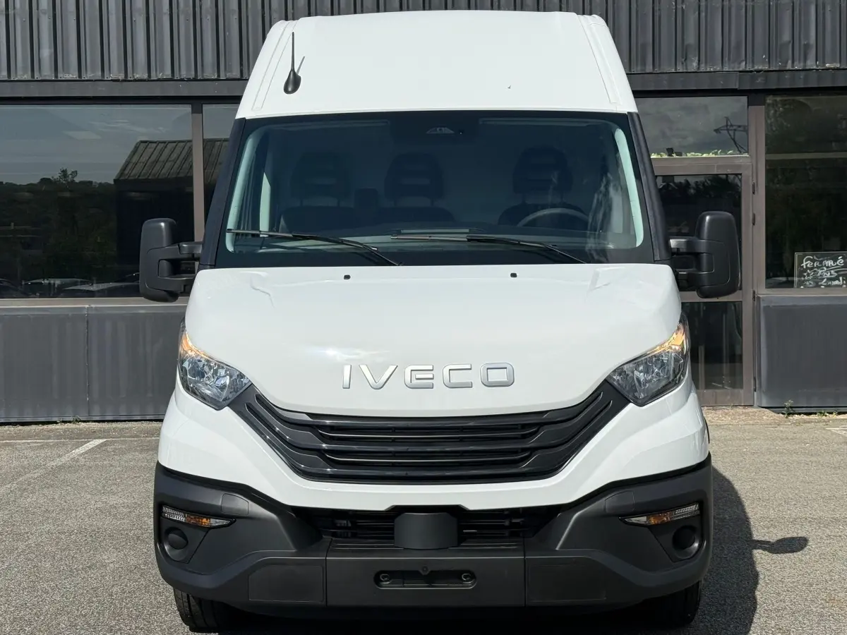 Vue frontale d’un utilitaire Iveco Daily blanc 2026 avec calandre noire et phares halogènes allumés.