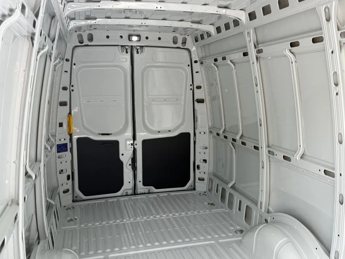 Vue intérieure arrière du fourgon Iveco Daily blanc 2026, montrant l’espace de chargement vide et les portes arrière fermées.