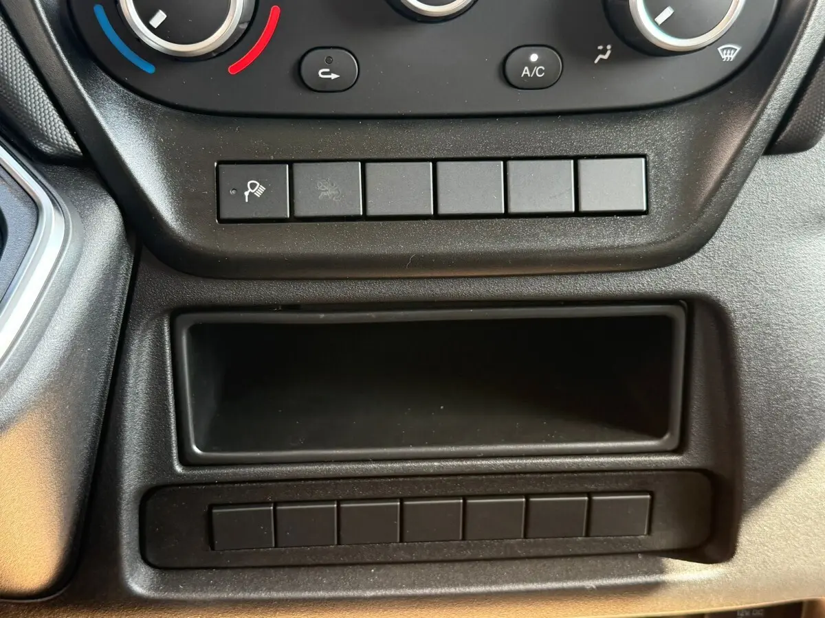 Détail du tableau de bord noir du Iveco Daily 35S18 avec commandes de climatisation et rangements.
