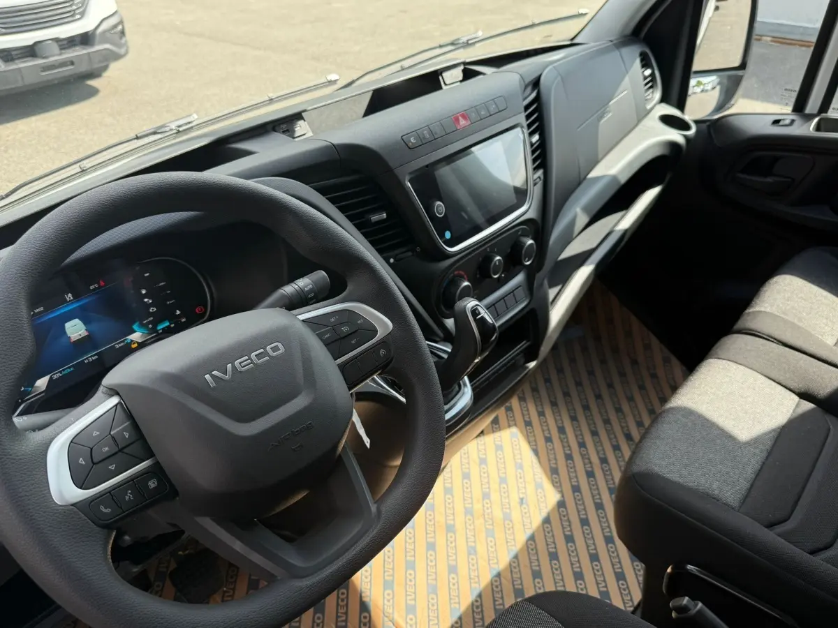 Vue intérieure côté conducteur de l'IVECO Daily blanc 2026, volant multifonction et tableau de bord moderne avec écran tactile.