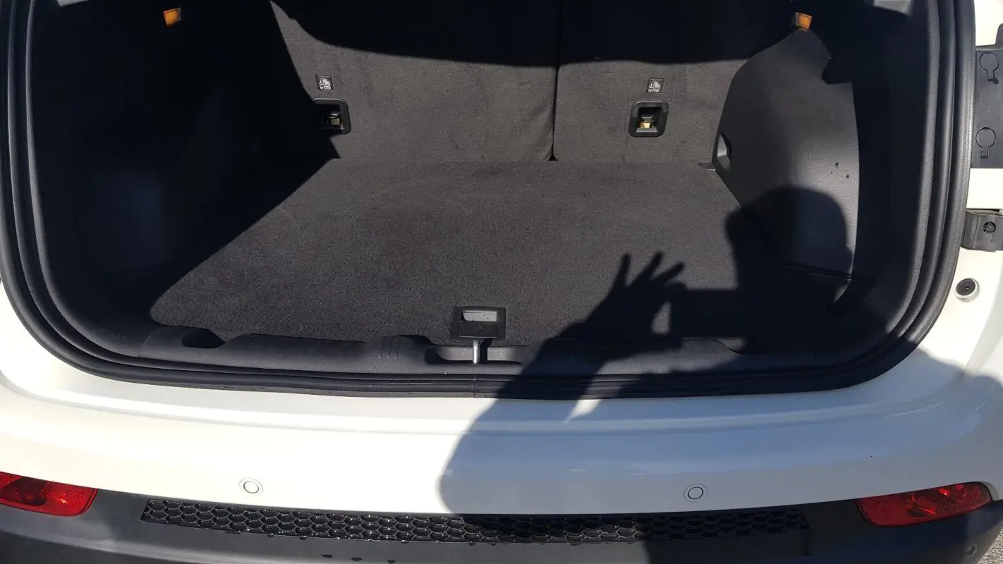 Coffre ouvert vu de l'arrière d'un Jeep Compass blanc 2024 avec tapis de sol noir et feux arrière visibles.