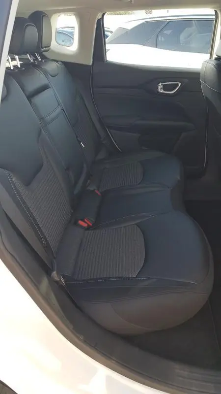 Vue intérieure côté gauche des sièges arrière noirs du Jeep Compass blanc 2024, avec ceinture et appuie-têtes visibles.