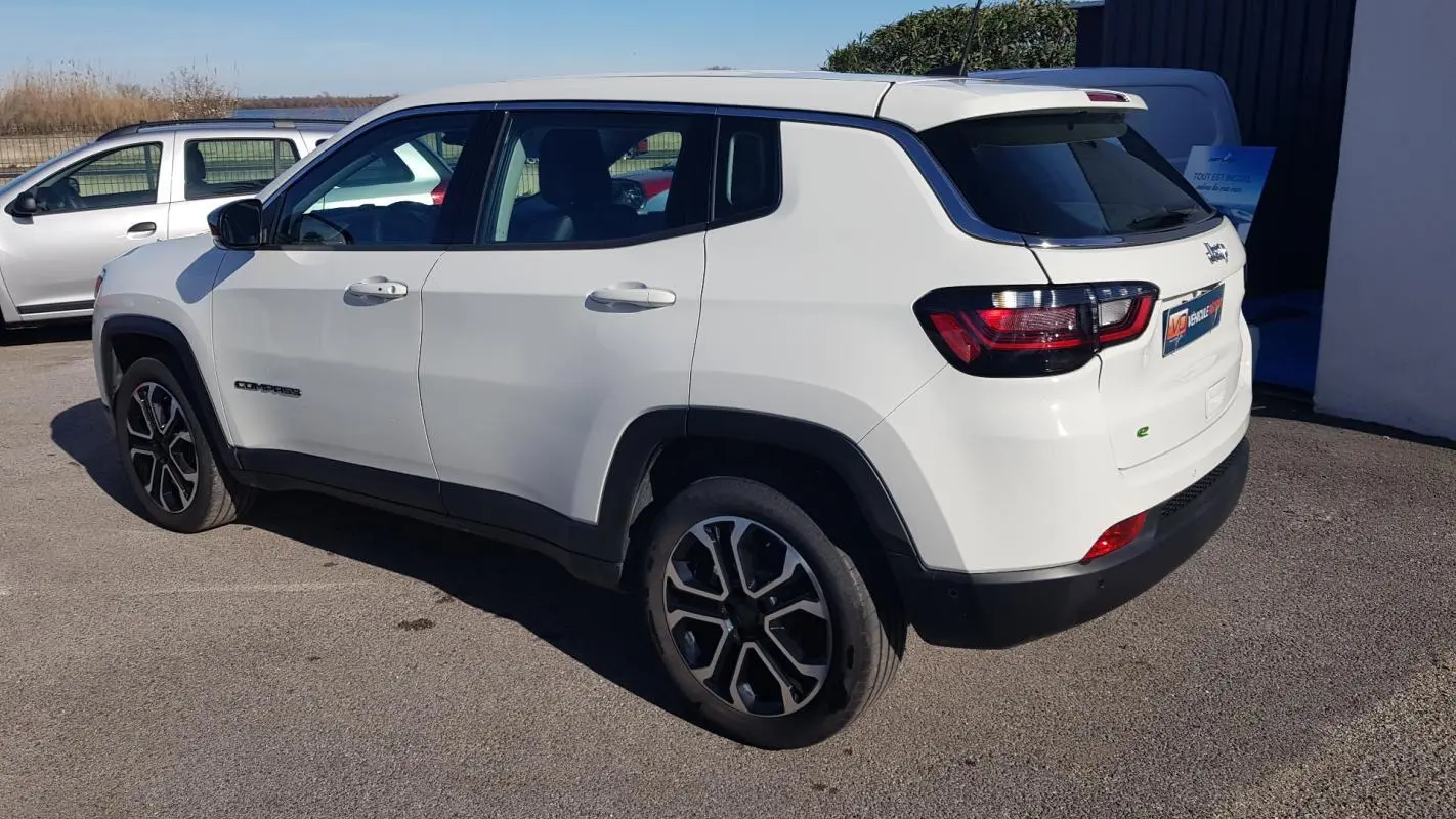 Jeep Compass blanc vu en 3/4 arrière côté gauche, avec jantes alliage 18 pouces et feux arrière LED.