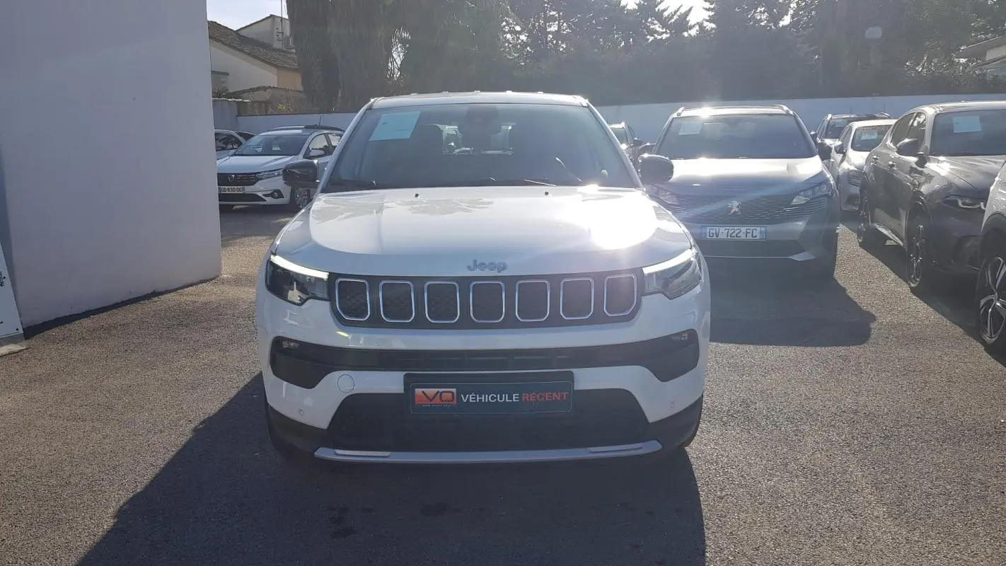 Vue avant d'un Jeep Compass blanc 2024 avec calandre à sept fentes et phares LED allumés.