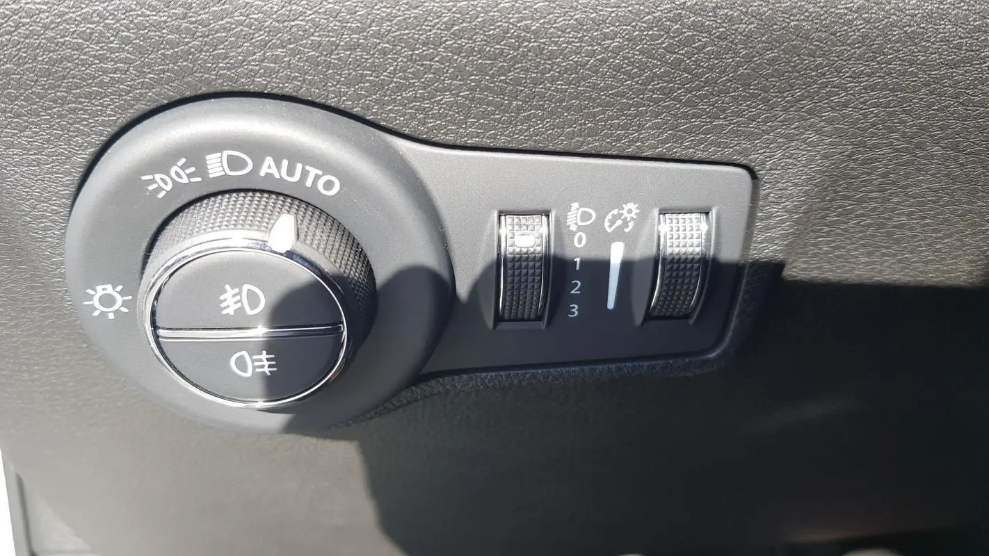 Gros plan sur la commande des phares et réglages d’éclairage du tableau de bord du Jeep Compass blanc 2024.