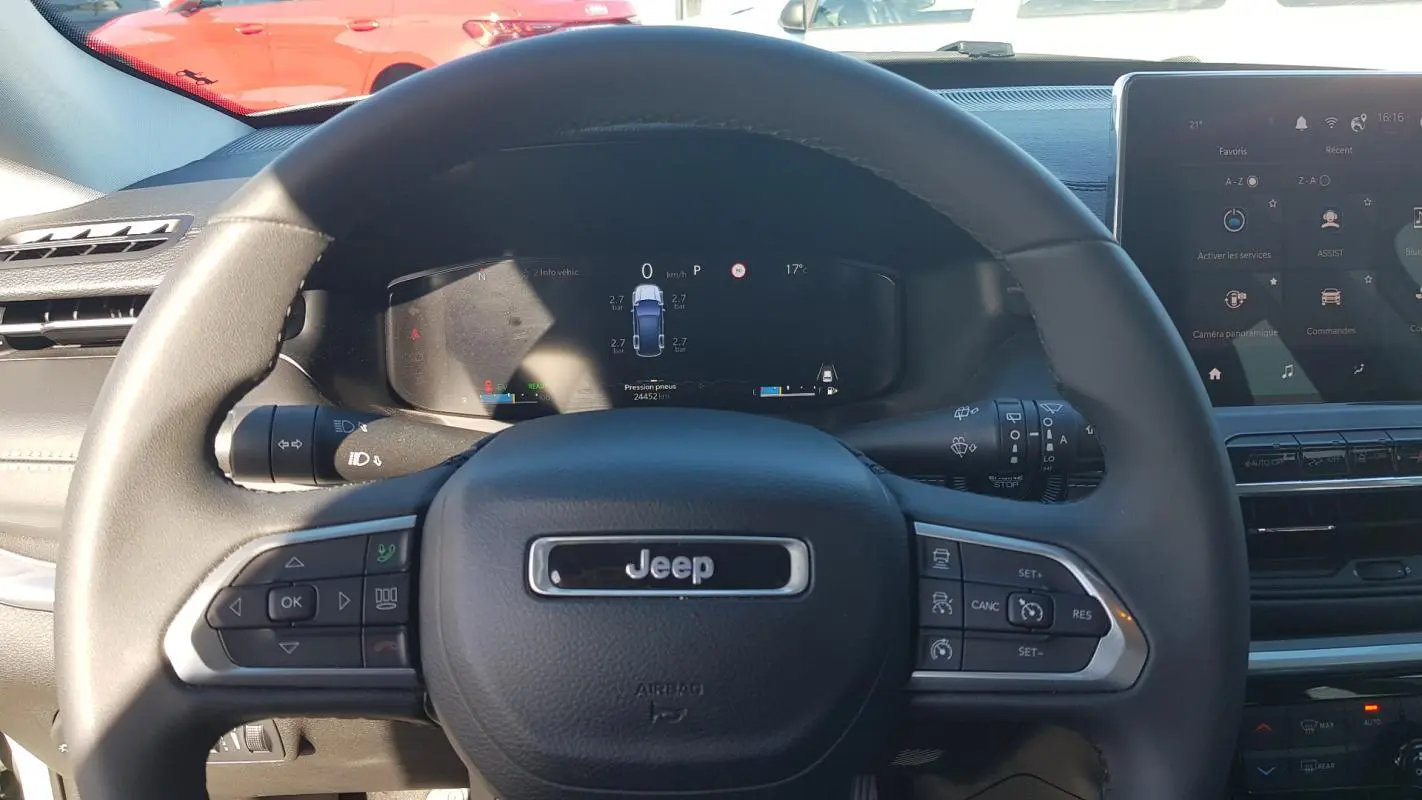 Vue centrée sur le volant noir du Jeep Compass 2024 avec tableau de bord numérique et écran tactile.