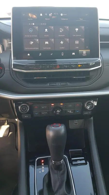 Vue rapprochée de la console centrale du Jeep Compass blanc 2024, avec écran tactile et levier de boîte auto.