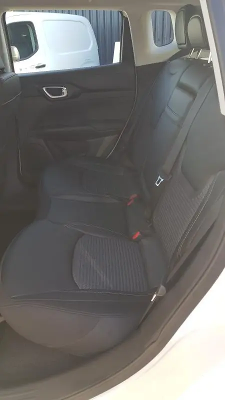 Vue intérieure côté arrière droit du Jeep Compass blanc 2024, montrant les sièges arrière noirs avec ceinture de sécurité.
