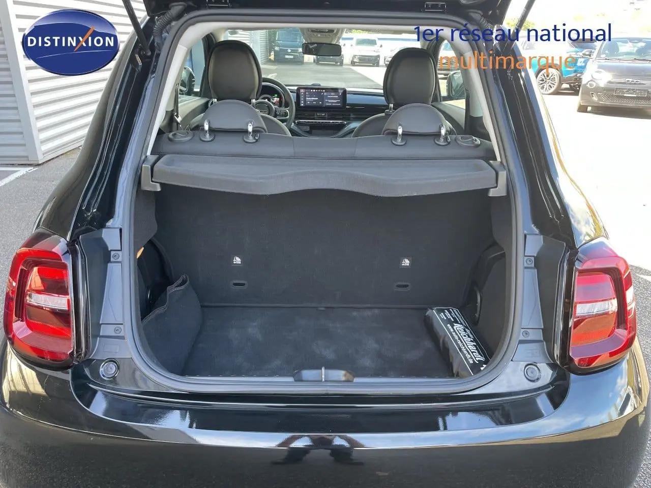 Vue arrière du coffre ouvert d'une Fiat 500 électrique noire Onyx 2023, avec intérieur et sièges visibles.