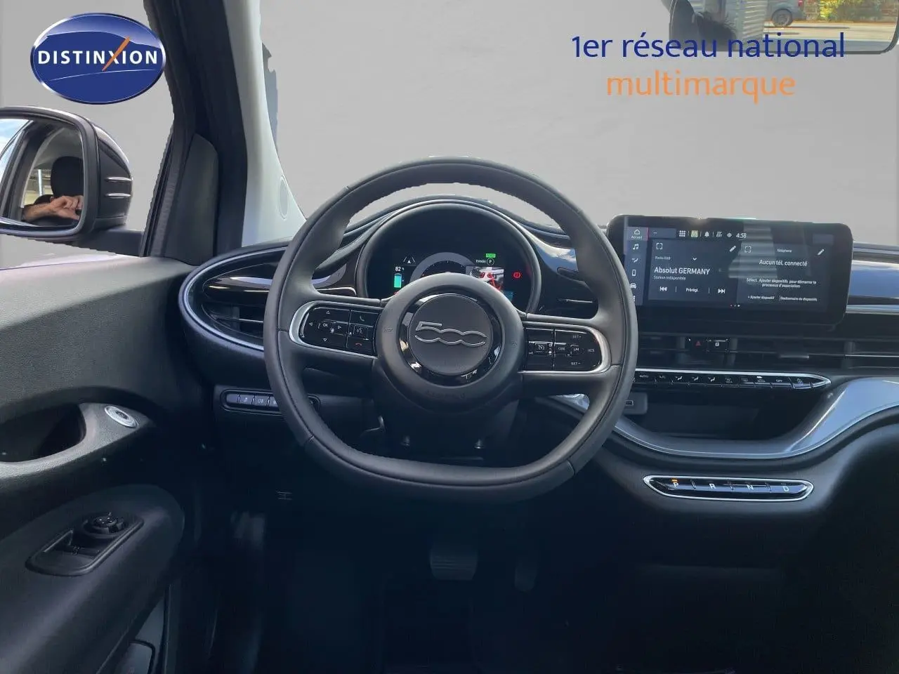 Vue intérieure frontale du tableau de bord noir onyx de la FIAT 500 électrique 2023 avec volant cuir et écran tactile.