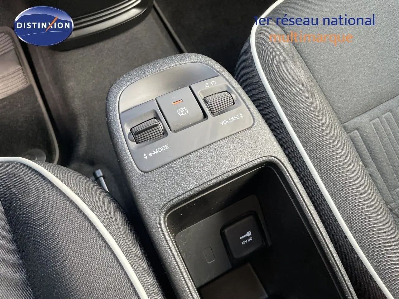 Vue rapprochée de la console centrale de la Fiat 500 électrique noire, avec commandes e-mode et volume visibles.
