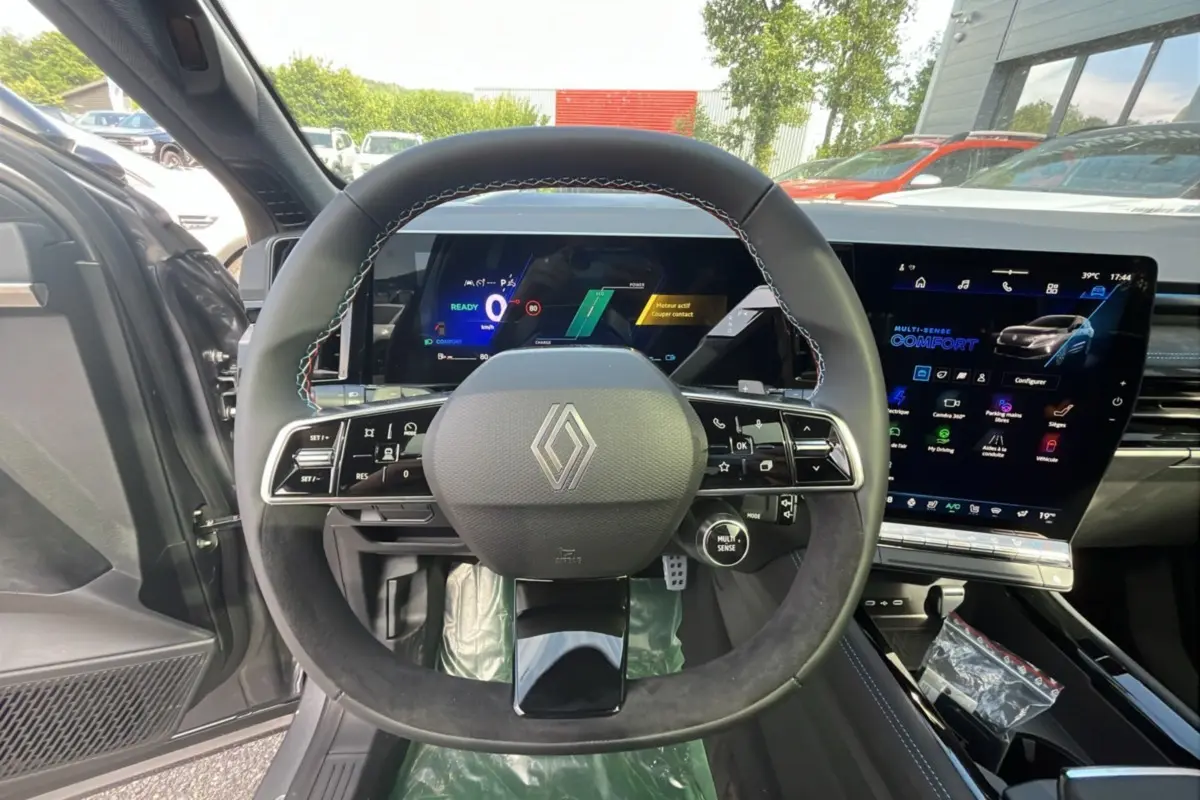 Vue intérieure centrée sur le volant cuir multifonctions du Renault Austral gris schiste avec écran digital et toit panoramique.