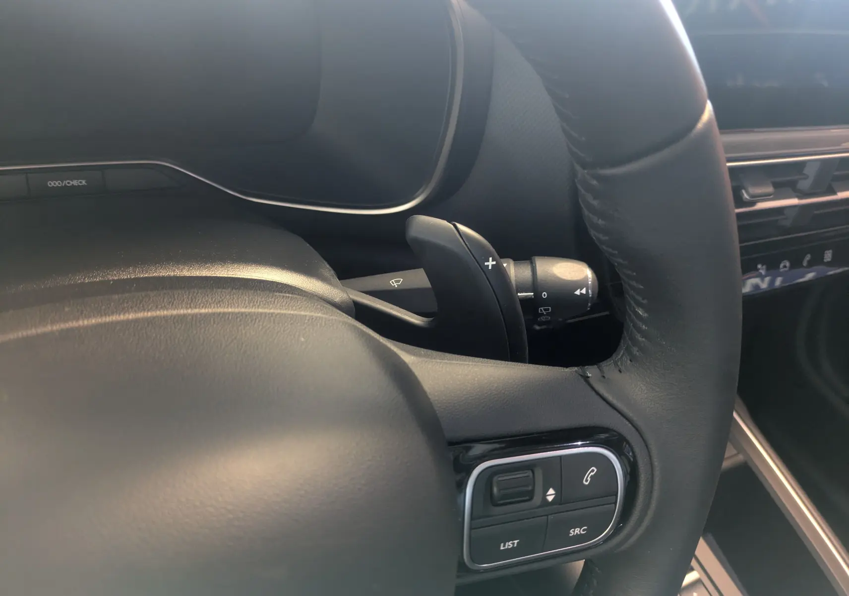Gros plan sur le volant cuir noir du Citroën C5 Aircross hybride 2024 avec commandes intégrées et palettes au volant.