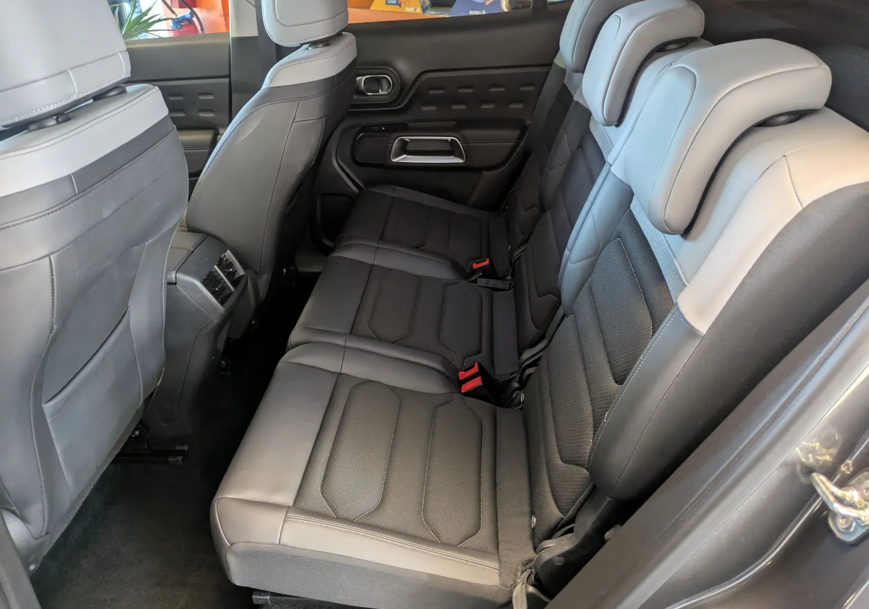 Vue latérale droite de l'intérieur arrière du Citroën C5 Aircross hybride gris platinium, sièges en tissu gris structuré et cuir effet gris.