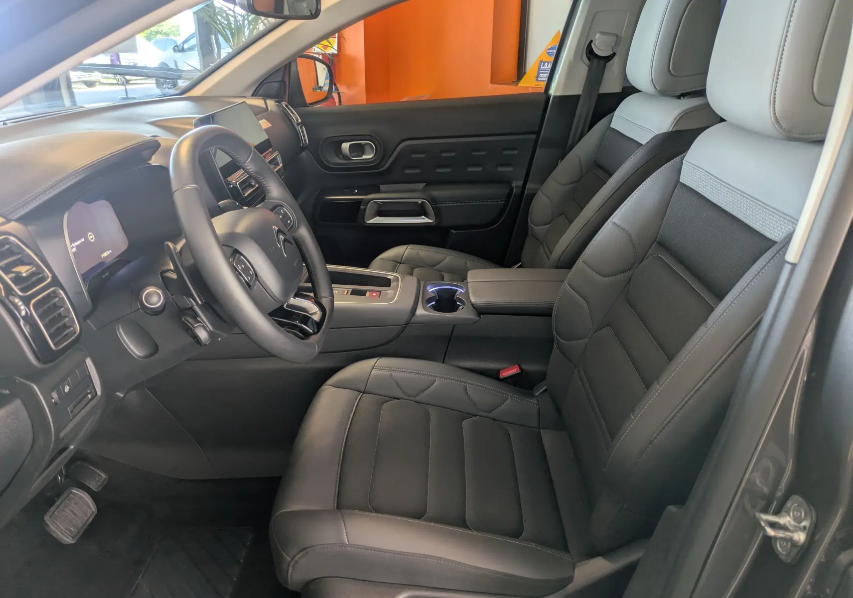 Vue intérieure côté conducteur du Citroën C5 Aircross hybride 2024, sièges en cuir gris et tableau de bord moderne.