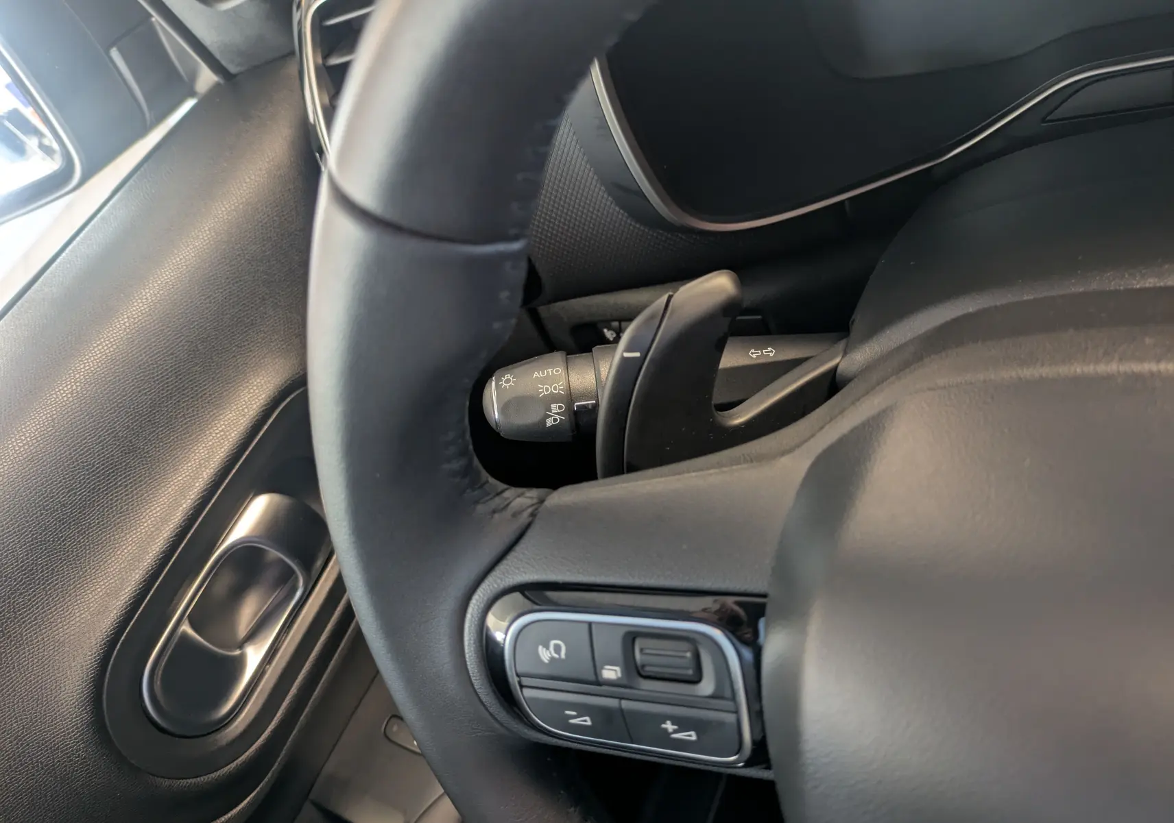 Gros plan sur le volant en cuir noir du Citroën C5 Aircross hybride, avec commandes intégrées côté gauche.